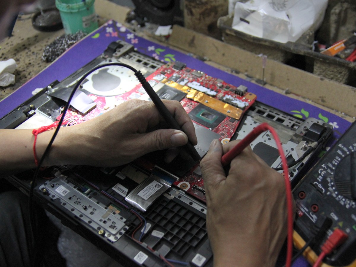 Technician diagnosing a motherboard with a multimeter